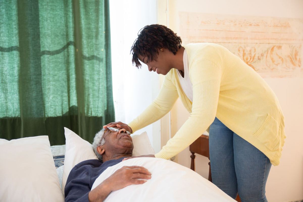 Caregiver tucking in a resting senior man at home