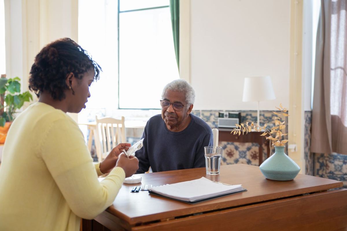 Caregiver sitting at the kitchen table with a senior man, talking through his day
